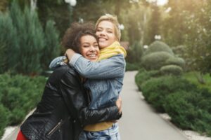 Dos amigas abrazándose en un parque, simbolizando el poder de los abrazos en el Día Mundial del Abrazo.