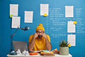 Persona abrumada frente a su escritorio lleno de tareas, representando visualmente la procrastinación